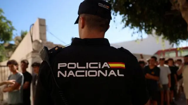 شرطي يقف للحراسة وظهره للكاميرا، بينما يصطف أطفال خارج مركز للشرطة لتسجيل بياناتهم لدى السلطات