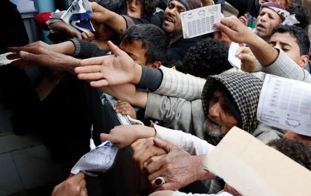 رجال يمدون أيديهم نحو المنصة حاملين أوراقاً رسمية.