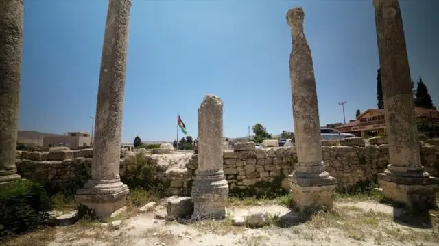 أعمدة أثرية من الموقع الأثري في سبسطية، في الضفة الغربية المحتلة ويظهر في المتتصف العلم الفلسطيني مرفرفاً. الصورة التقطت نهاراً.