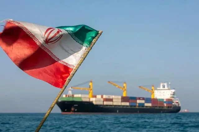 يرفرف العلم الإيراني مع هبوب الرياح فيما تبقى السفن راسية في مضيق هرمز بالقرب من جزيرة لارك الإيرانية، في 16 مايو/أيار 2026.