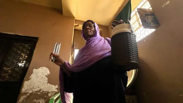 امرأة من السودان تحمل حافظة الصلح بيدها اليسرى.