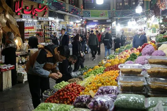 سوق للخضراوات والمواد الغذائية في طهران ليلا ويظهر فيه بعض المتسوقين من رجال ونساء