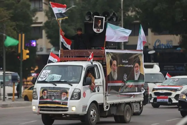 صورة تظهر رجل عراقي يلوح بعلم بلاده خلال تجمع مؤيد لإيران في ساحة التحرير ببغداد، 2 أبريل/ نيسان 2026. 