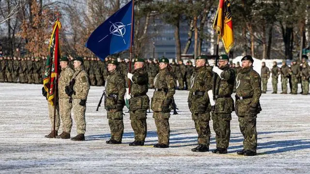 جنود ألمان يرتدون زياً مموهاً باللون الأخضر خلال عرض عسكري، يحملون علم حلف شمال الأطلسي (الناتو) في مراسم عامة لإحياء توسيع الالتزام العسكري الألماني في ليتوانيا، في 4 فبراير/شباط 2026 بمدينة كاوناس.