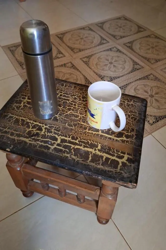 كأس بيضاء للقهوة، وُضعت على طاولة خشبية صغيرة